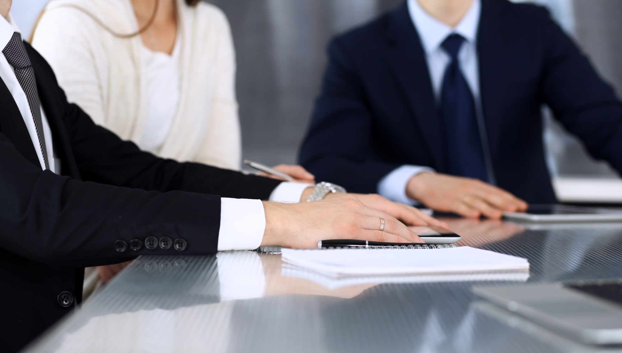 Business people discussing contract working together at meeting at the glass desk in modern office. Unknown businessman and woman with colleagues or lawyers at negotiation